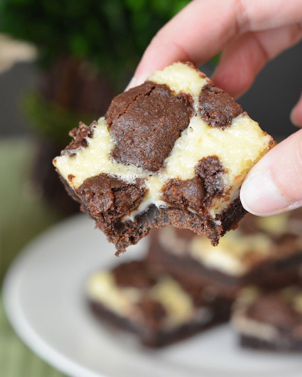 a hand holding a piece of chocolate cheesecake cookie