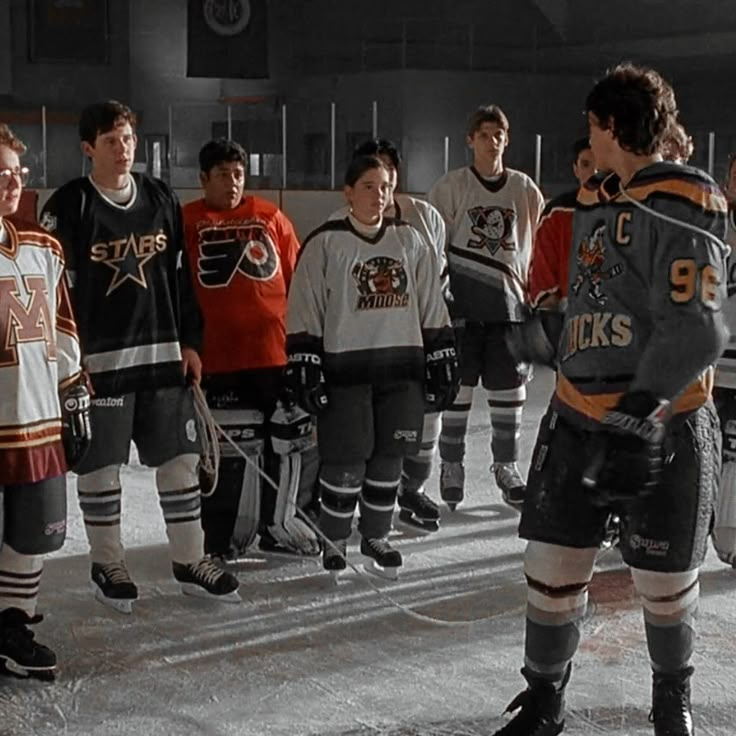 a group of young men standing next to each other on top of an ice rink