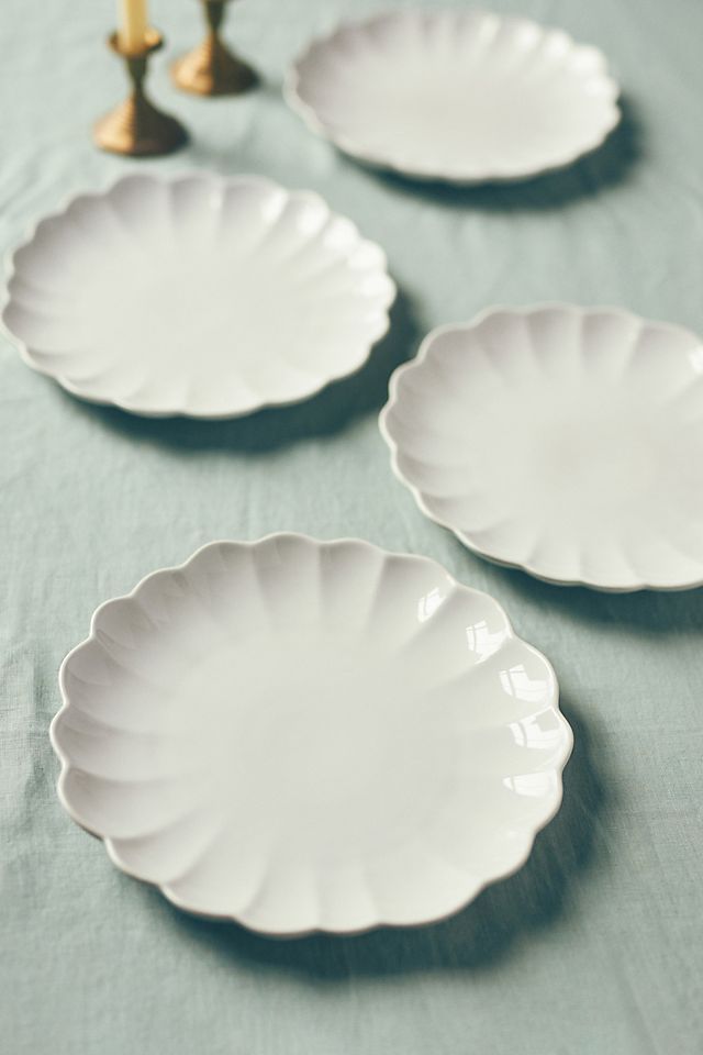 three white plates sitting on top of a table next to a gold candelabra