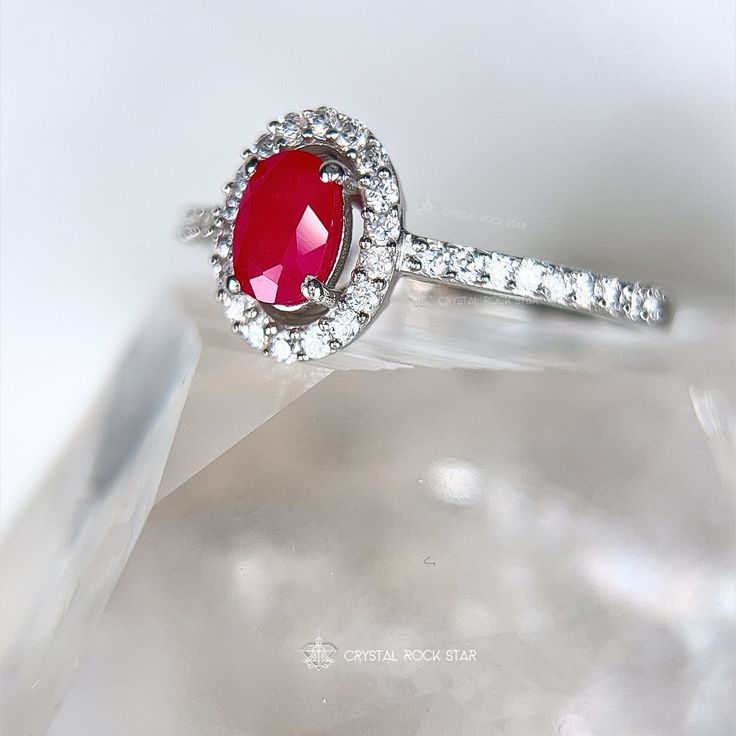 Genuine Ruby Oval Faceted Halo Sterling Silver Ring Add this beautiful pink Ruby halo ring and elevate your jewelry collection. This ring boasts an oval cut natural Ruby gemstone that exudes elegance and sophistication. The accented halo twinkles around the opaque Ruby, while the pave band will take your breath away with its sparkling accent stones. Whether you're treating yourself or looking for the perfect gift for a loved one, this Ruby ring is a beautiful choice for someone looking for a memorable design. Makes a stunning gift for a July birthday recipient as Ruby is the July birthstone. Ruby is considered a stone of love and vitality. Ruby is part of the Corundum crystal family and gets its beautiful pink tones from trace mineral elements of chromium. Sizes Available: 5, 7, 8, 9 DIMEN Luxury Oval Ruby Ring With Halo Design, Oval Ruby Halo Ring With Center Stone, Red Oval Halo Ring With Center Stone, Oval Ruby Halo Ring Fine Jewelry, White Gold Ruby Ring With Halo, Elegant Oval Ruby Ring With Halo, Elegant Oval Halo Ruby Ring, Red Oval Halo Ring, Oval Ruby Halo Jewelry