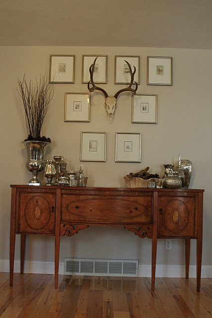 a wooden table topped with pictures and vases on top of it's sideboard