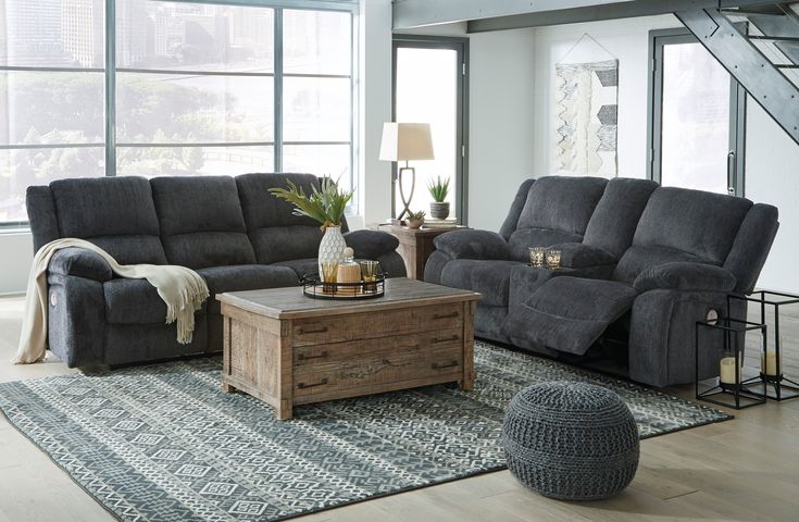 a living room filled with furniture and a stair case in front of a large window