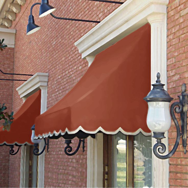 a red awning on the side of a brick building next to a lamp post