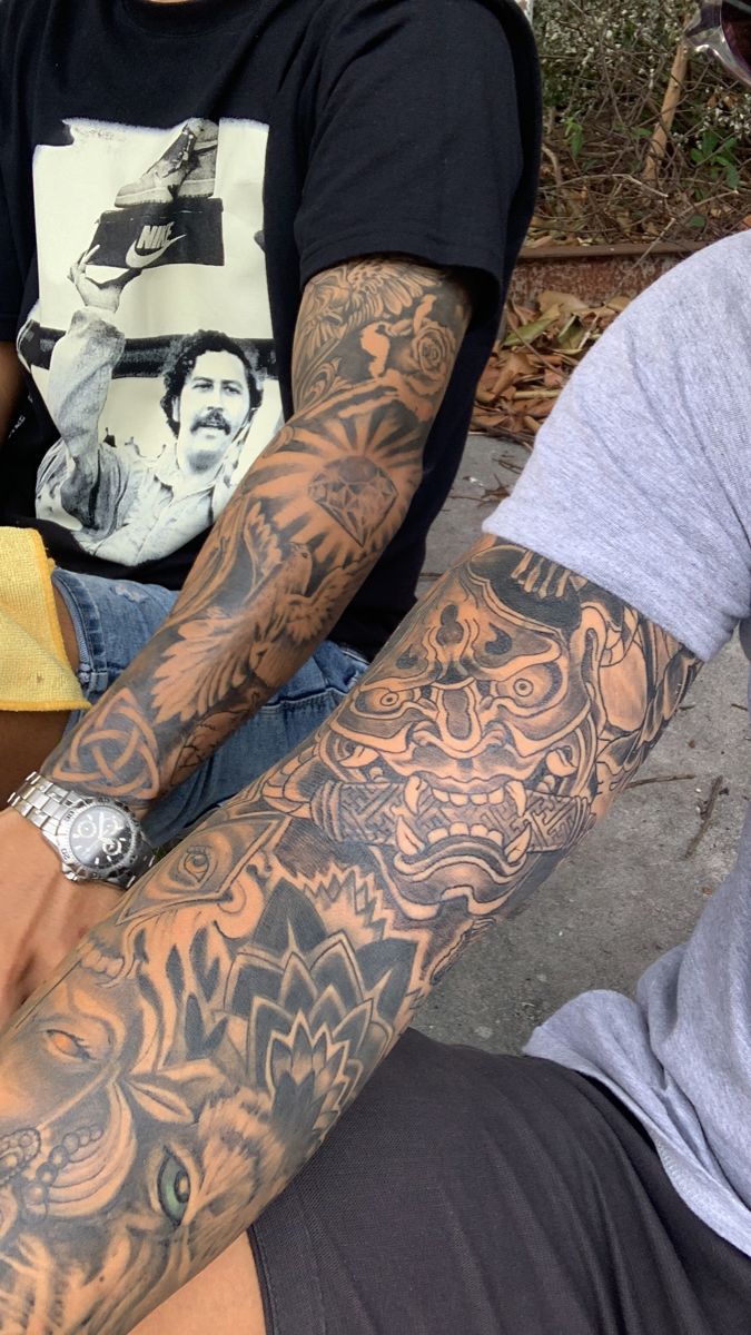 two men sitting next to each other with tattoos on their arms