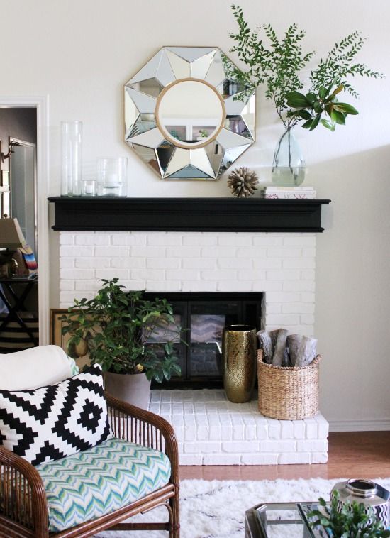 a living room filled with furniture and a fire place in front of a white brick fireplace