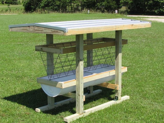 a wooden bench sitting on top of a lush green field next to a metal roof