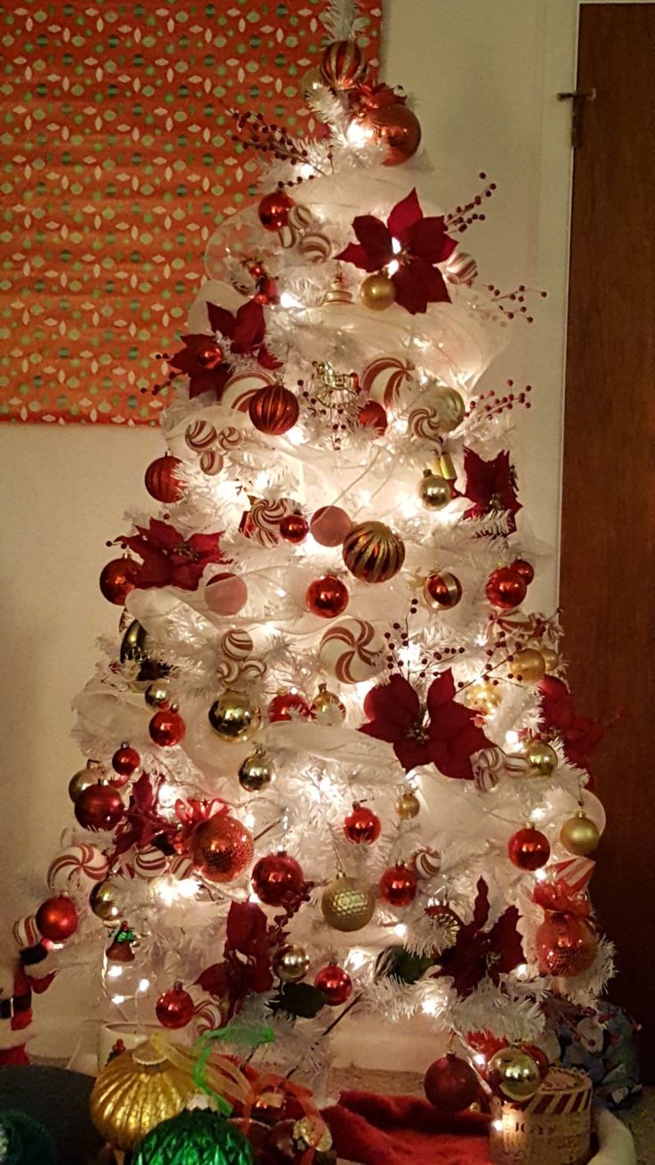 a white christmas tree with red and gold ornaments