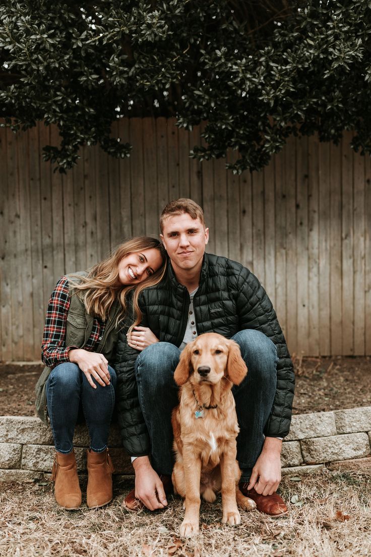 a man and woman sitting next to a brown dog