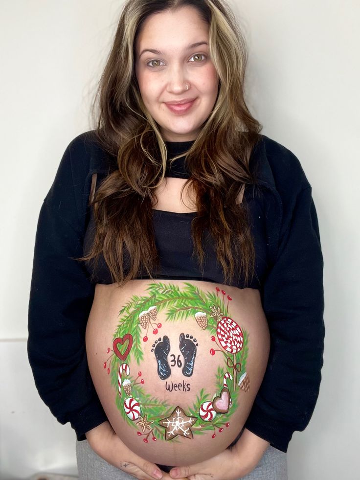 a pregnant woman is holding her belly with christmas decorations on it and the bottom half of her stomach