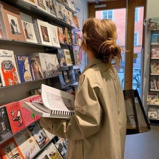 a woman standing in front of a bookshelf with lots of books on it