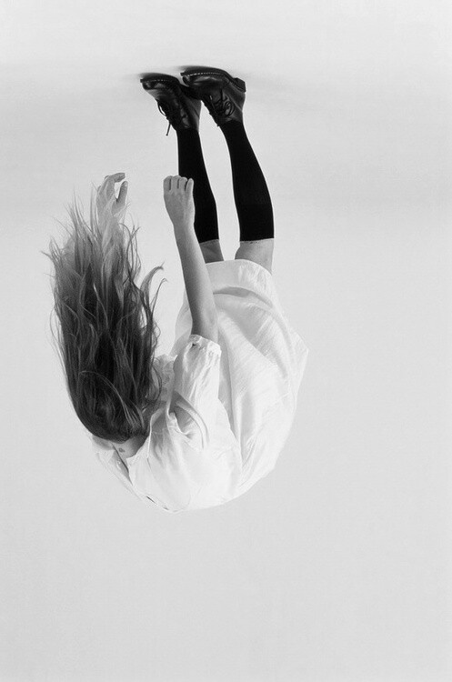 a woman flying through the air while riding a skateboard with her hair blowing in the wind