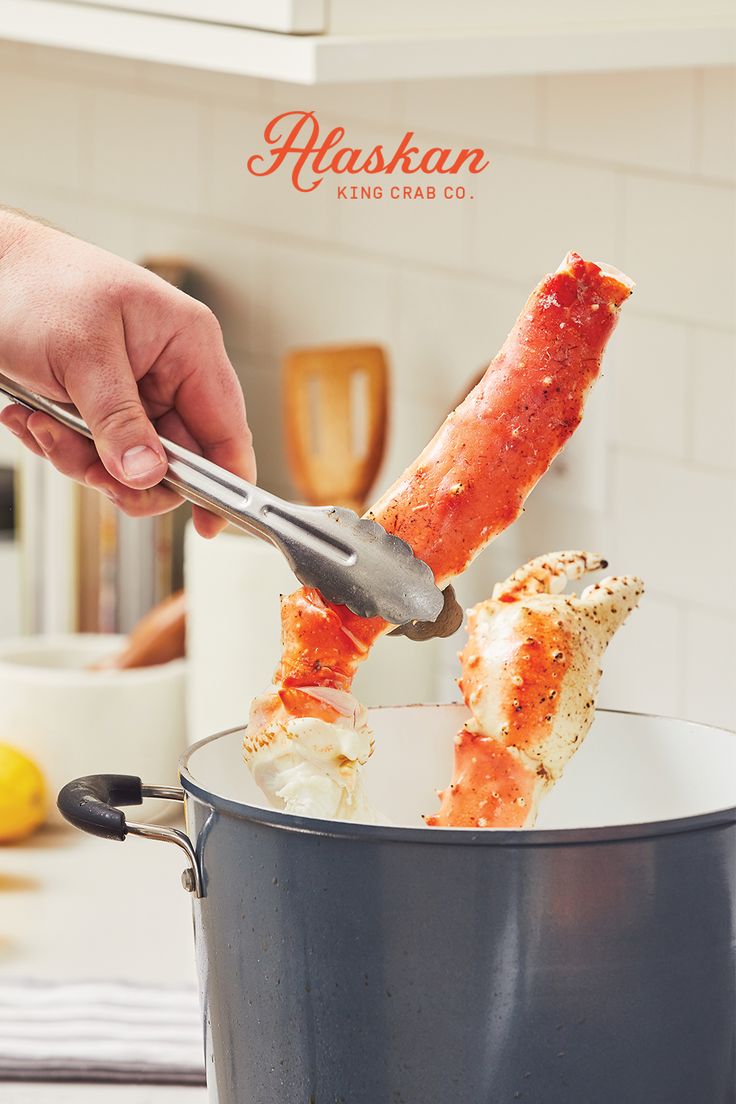 a person is holding a spatula over some crab legs in a pot on the kitchen counter