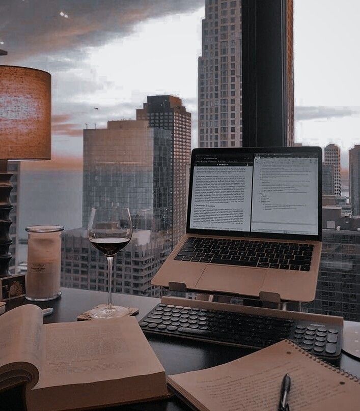 an open laptop computer sitting on top of a desk next to a glass of wine