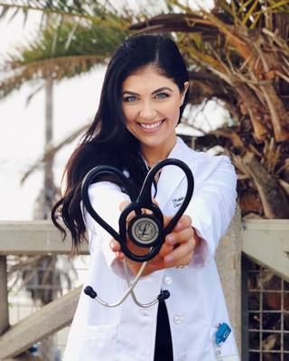 a woman in white coat holding up a stethoscope