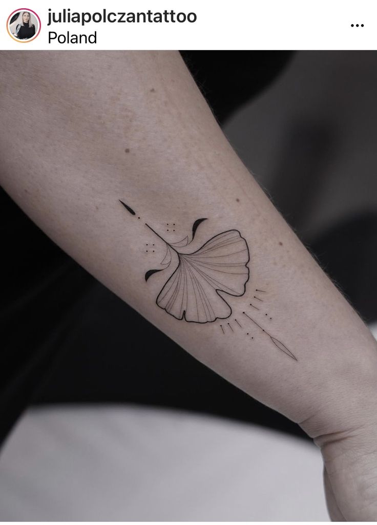 a person with a tattoo on their arm holding onto a white object in the shape of a ging sprout