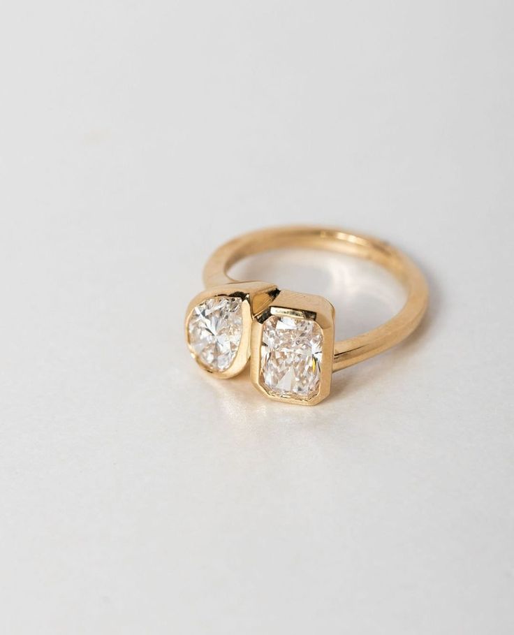 three stone gold ring with diamonds on the top and bottom, sitting on a white surface