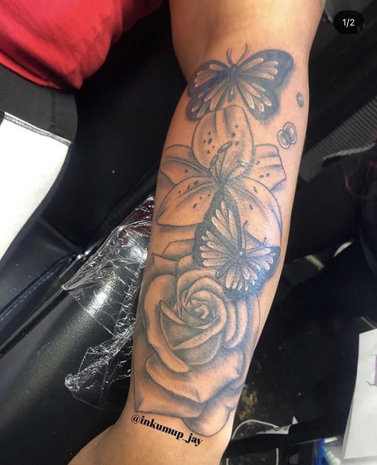 a woman's arm with a butterfly and roses tattoo on the left side of her arm