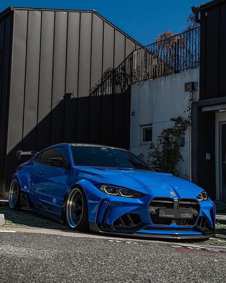 a blue sports car parked in front of a building