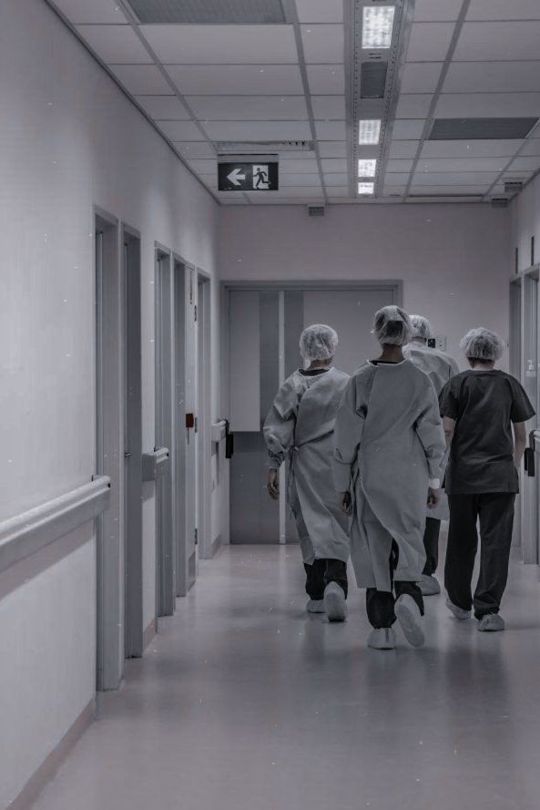 three people walking down a hallway in scrub suits