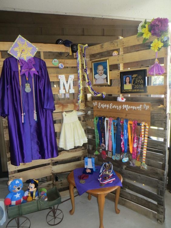 a room filled with wooden pallets covered in purple graduation gowns and other items