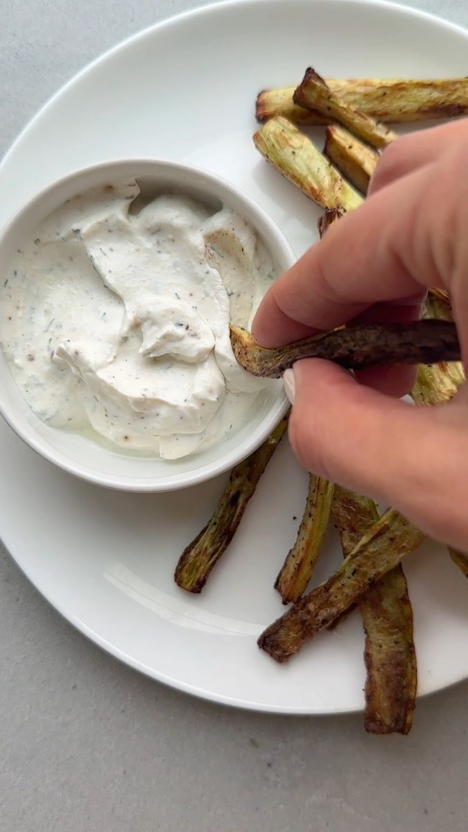 a person dipping some kind of sauce on top of asparagus fries with ranch dressing