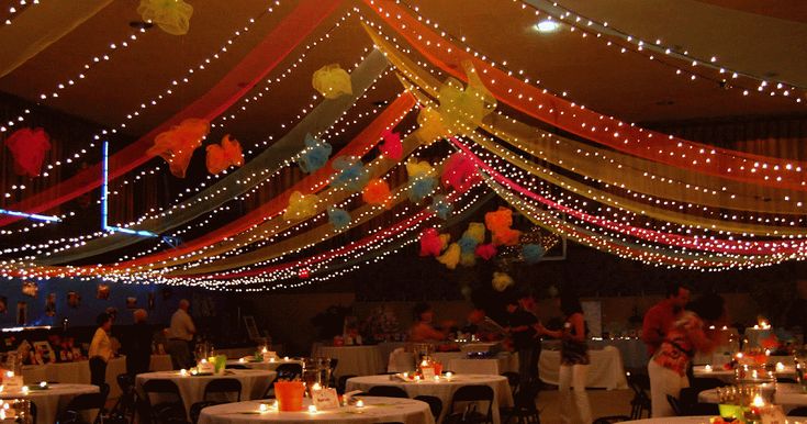 a room filled with lots of tables covered in white tablecloths and colorful lights