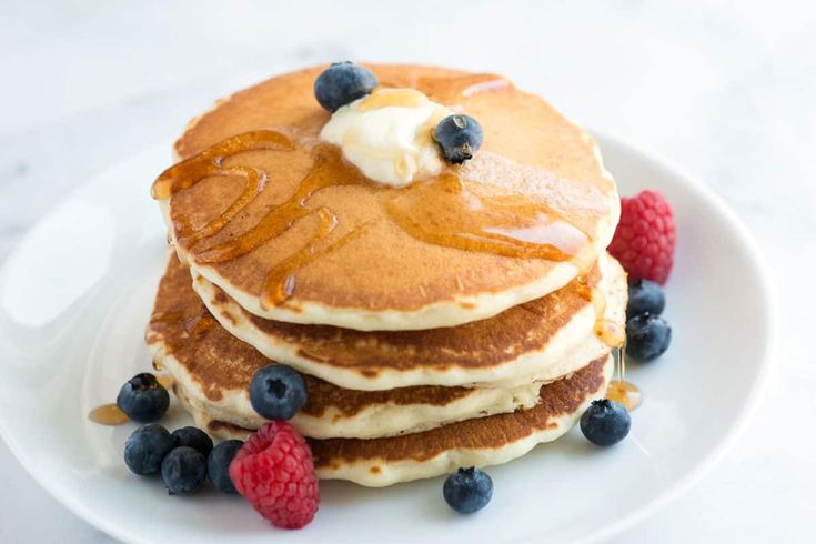 a stack of pancakes with blueberries and raspberries on top