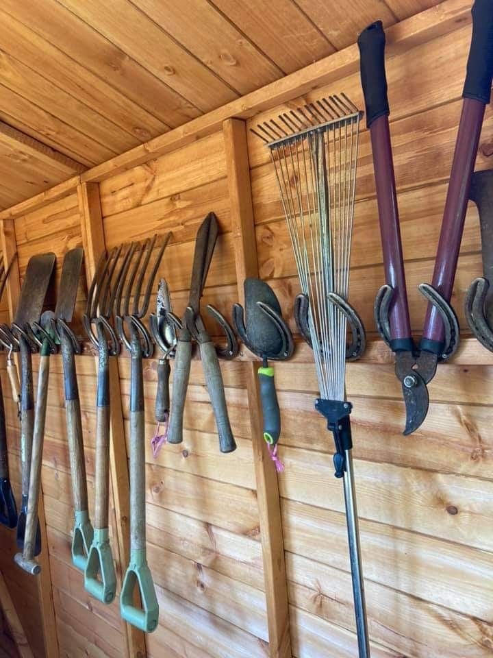 there are many garden tools hanging on the wall