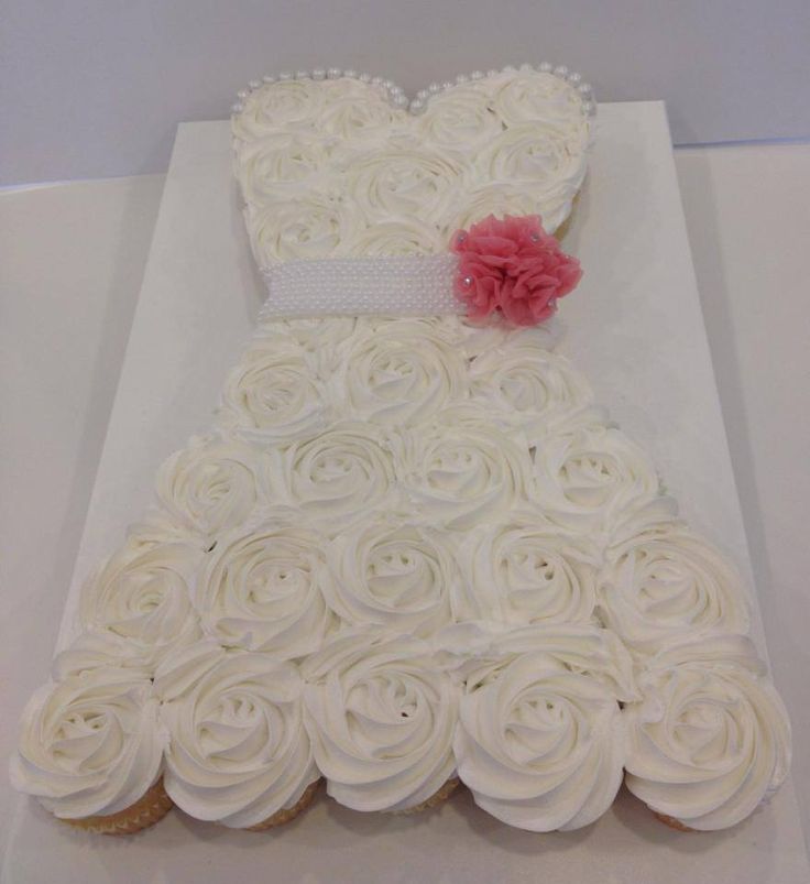 a dress made out of cupcakes on top of a white cake sheet with pink flowers