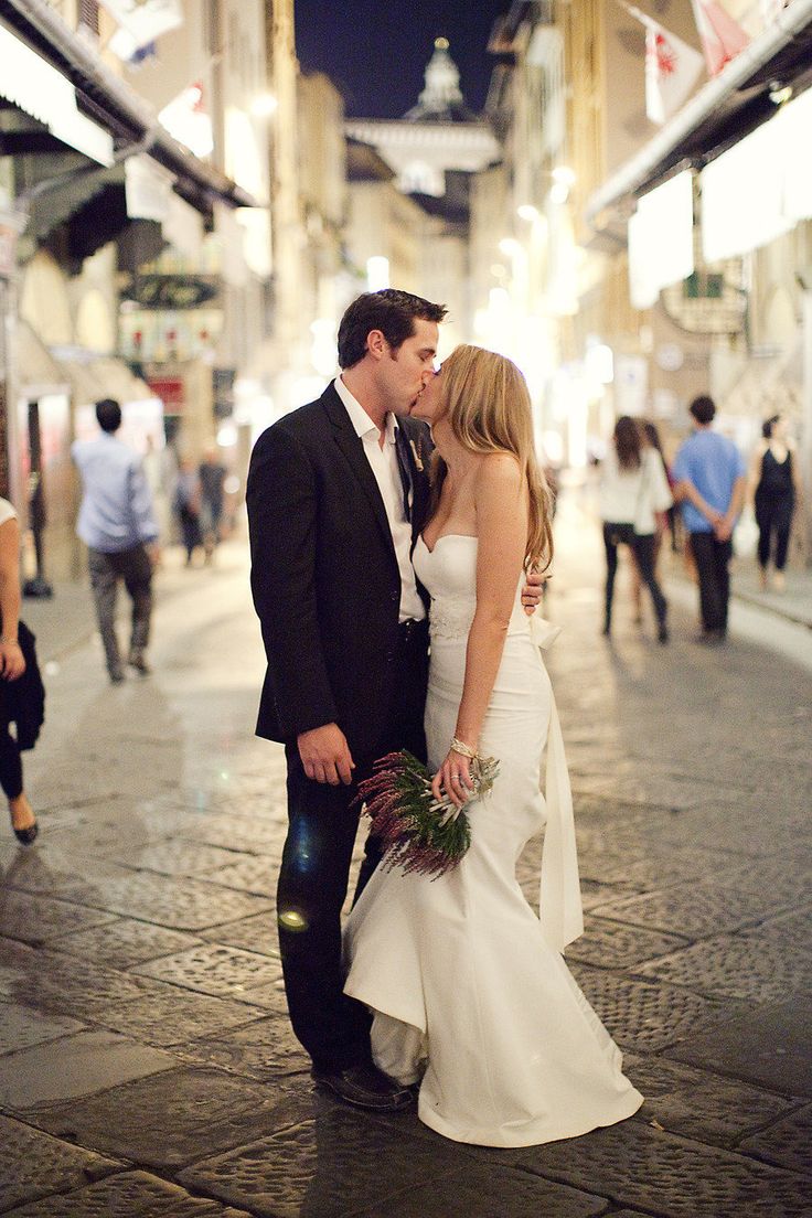 a bride and groom kissing on the street