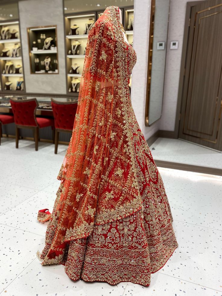 a red and gold bridal gown is on display in a room with many chairs