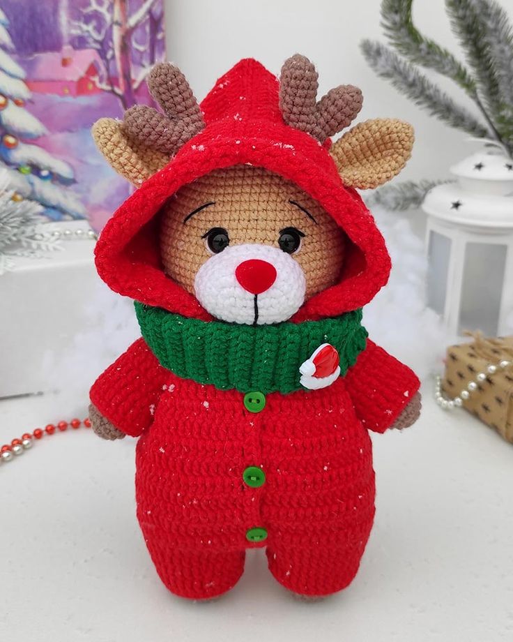 a stuffed animal wearing a red sweater and green scarf with a hood on it's head