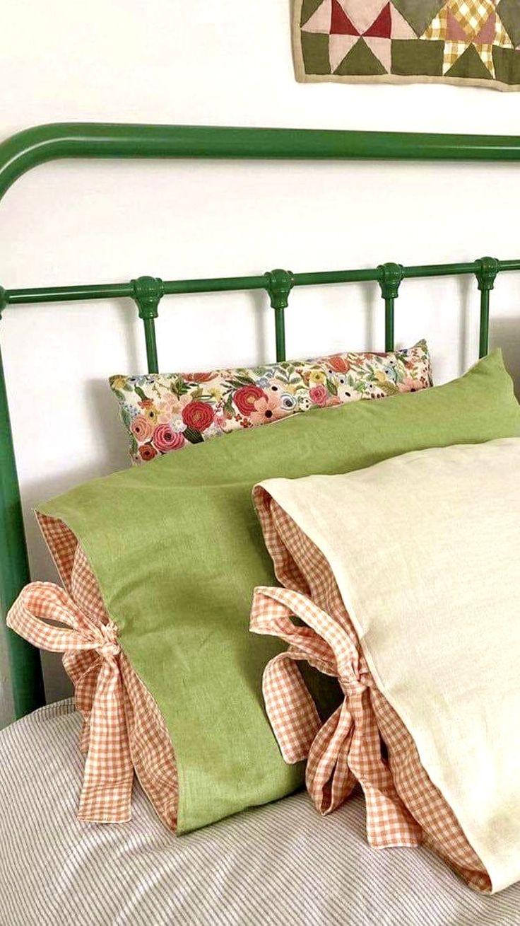 a green headboard with two pillows on top of it and a quilt hanging above the bed