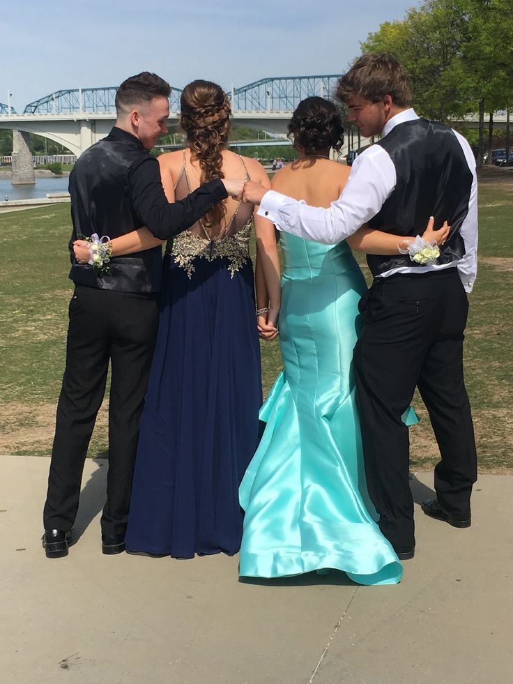 a group of people standing next to each other in front of a lake and bridge