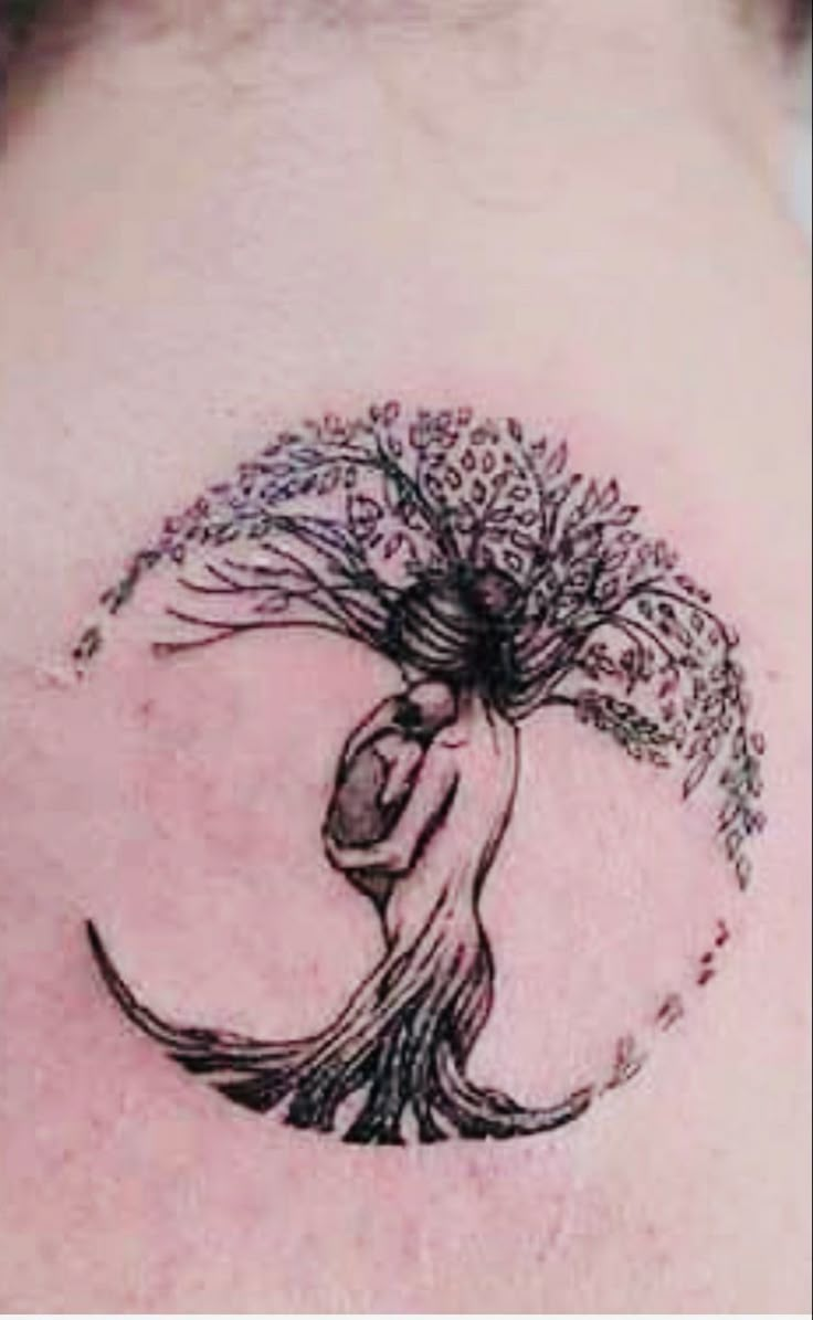 a woman's back with a tree tattoo on it