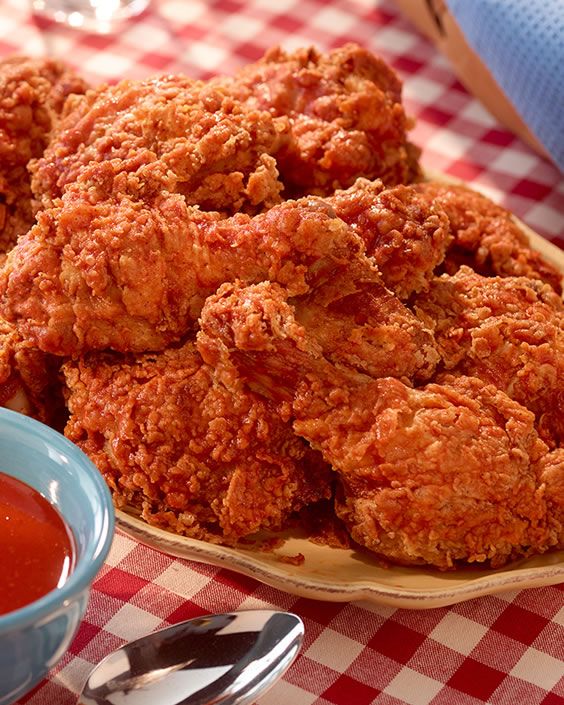 some fried food is on a wooden plate with sauce in a blue bowl next to it