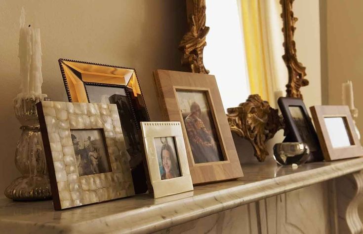 there are many frames on the mantle with candles in front of them and one is empty