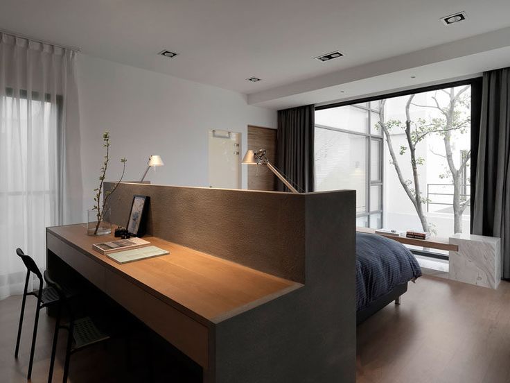 a room with a bed, desk and window