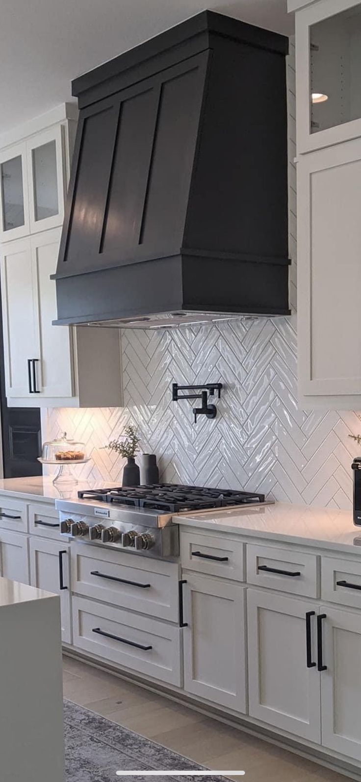 a kitchen with white cabinets and black stove top oven hood over the range in front of two microwaves