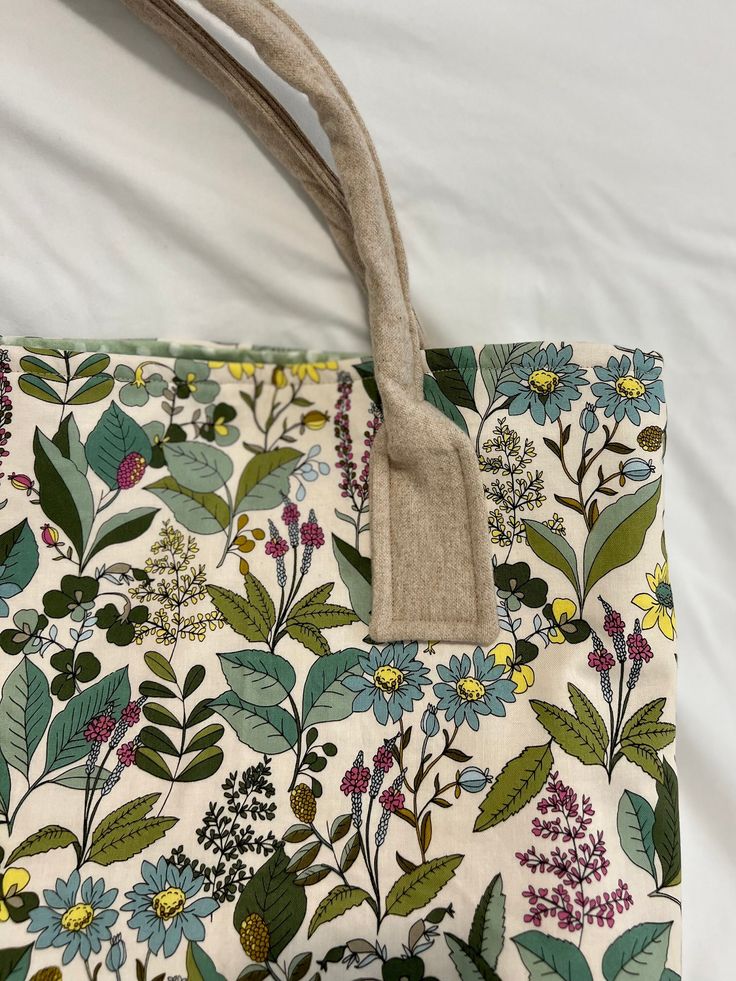 a floral bag with a tag hanging from it's handle on a bed sheet