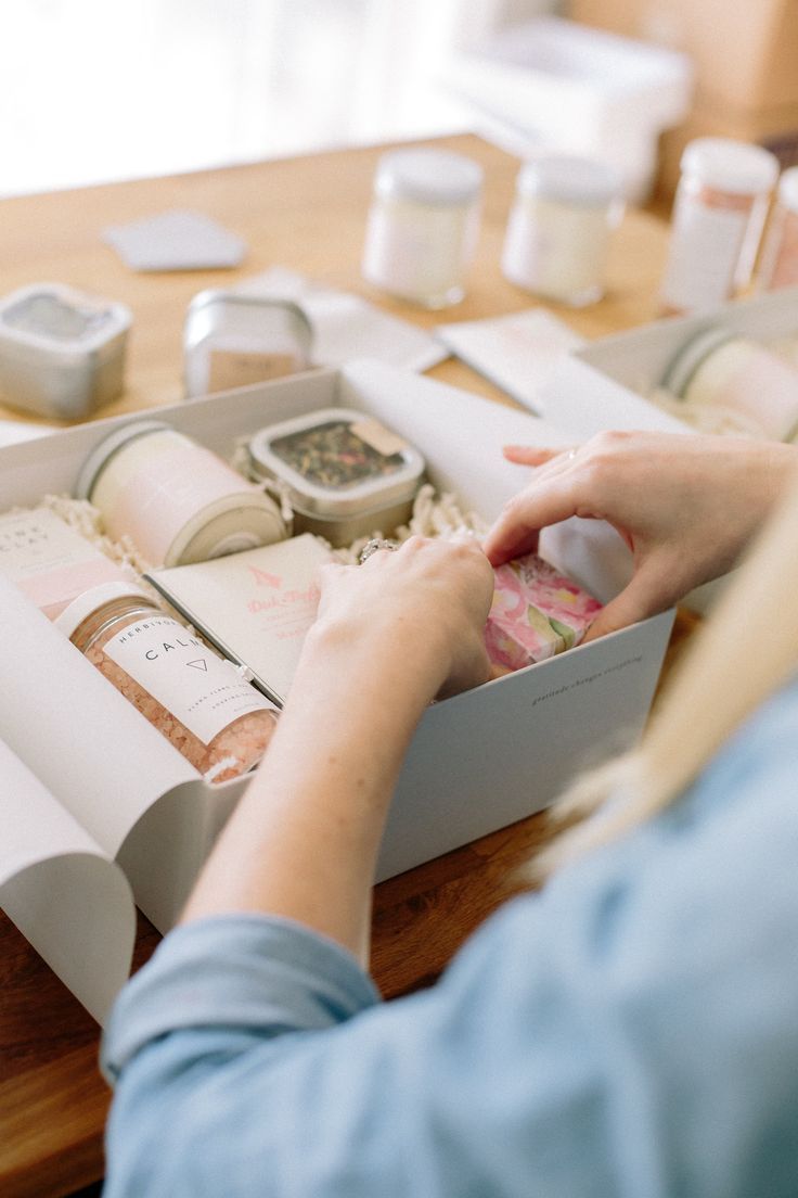 a woman is sitting at a table with her hands in a box and other items on the table