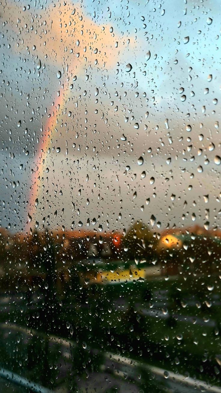 rain drops on a window with a rainbow in the background