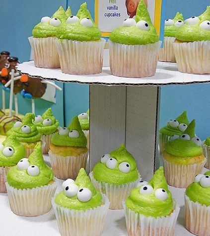 cupcakes with green frosting and googly eyes are on a cake stand