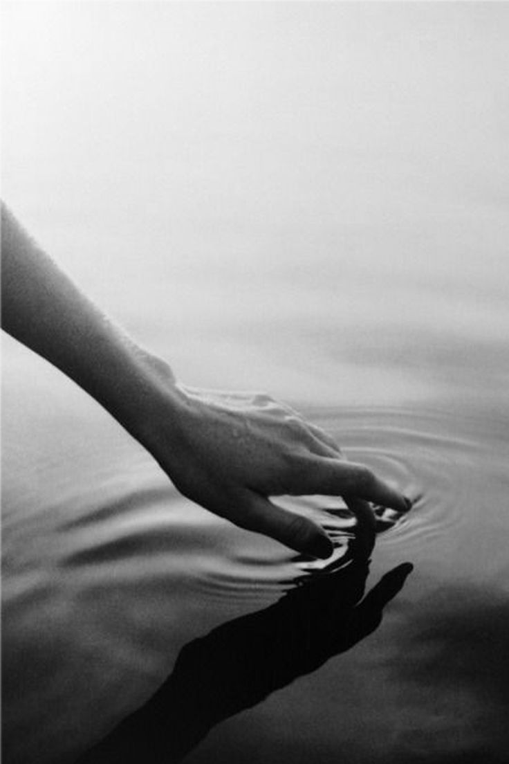 a person's hand reaching for something in the water