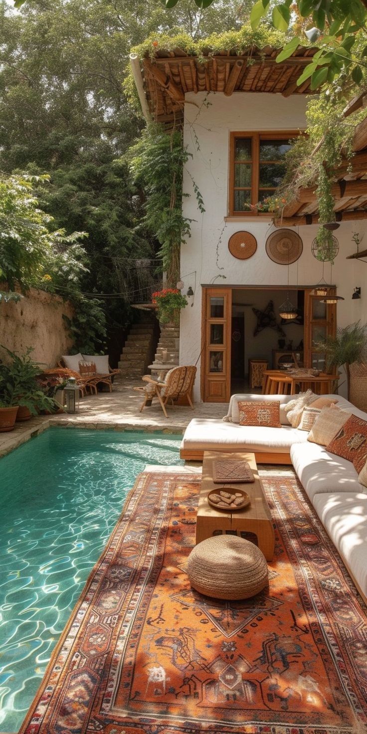 an outdoor living area next to a swimming pool with lounge chairs and rugs on the floor