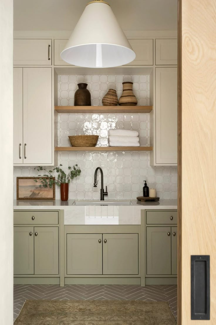 a kitchen with green cabinets and white counter tops is seen through an open door that leads to the dining room