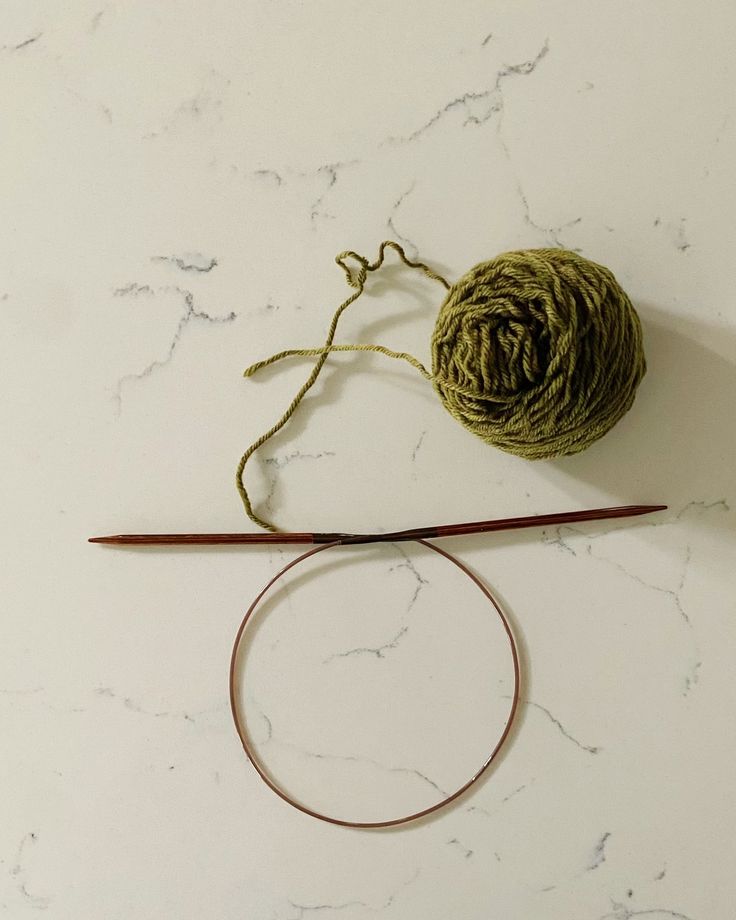 a ball of yarn sitting on top of a white table next to a knitting needle