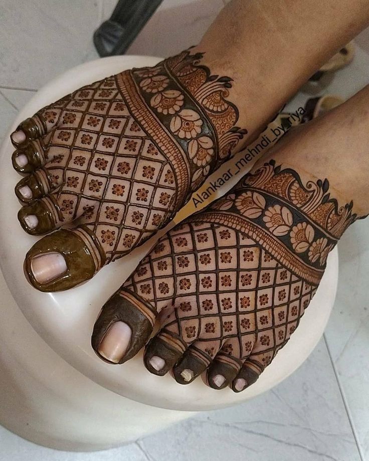 two feet with henna on them sitting on top of a toilet