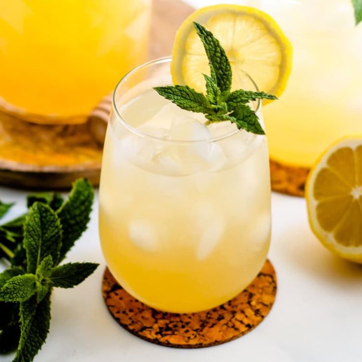 two glasses filled with lemonade and mint garnish next to sliced lemons