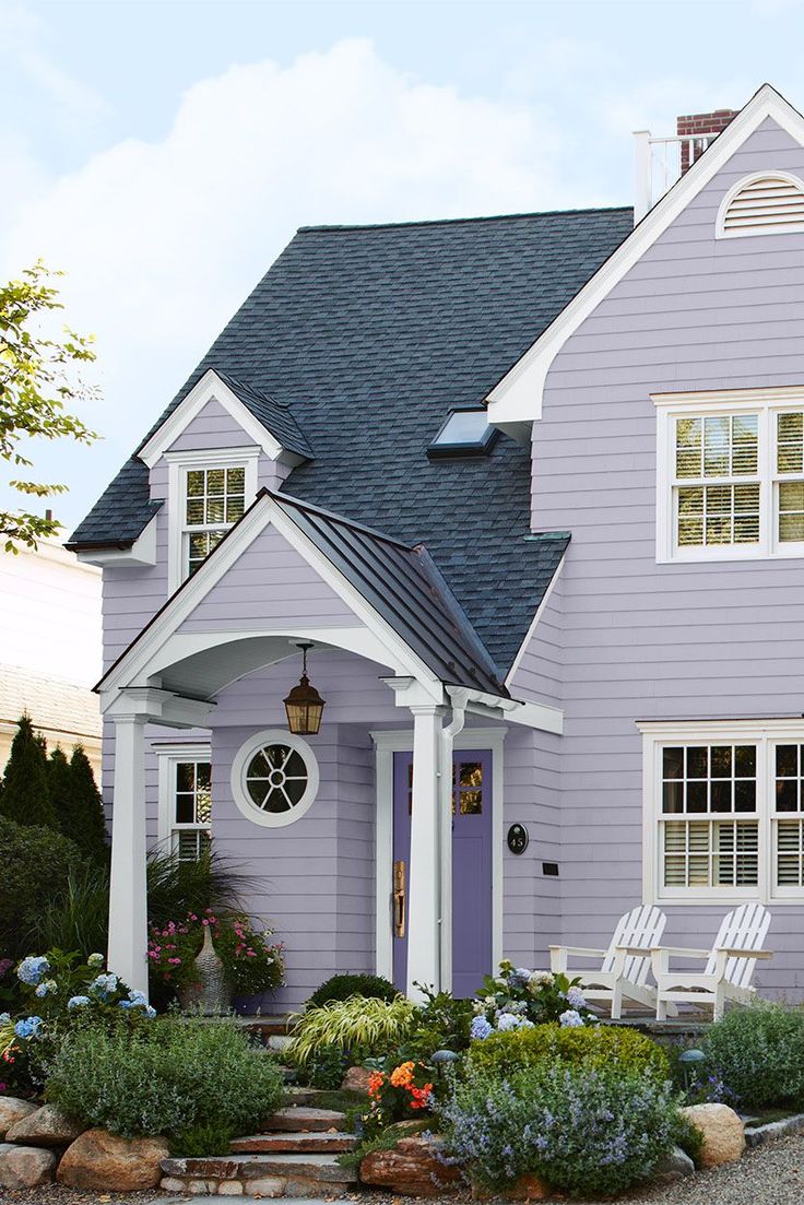 a purple house with white trim on the front door and windows, surrounded by landscaping